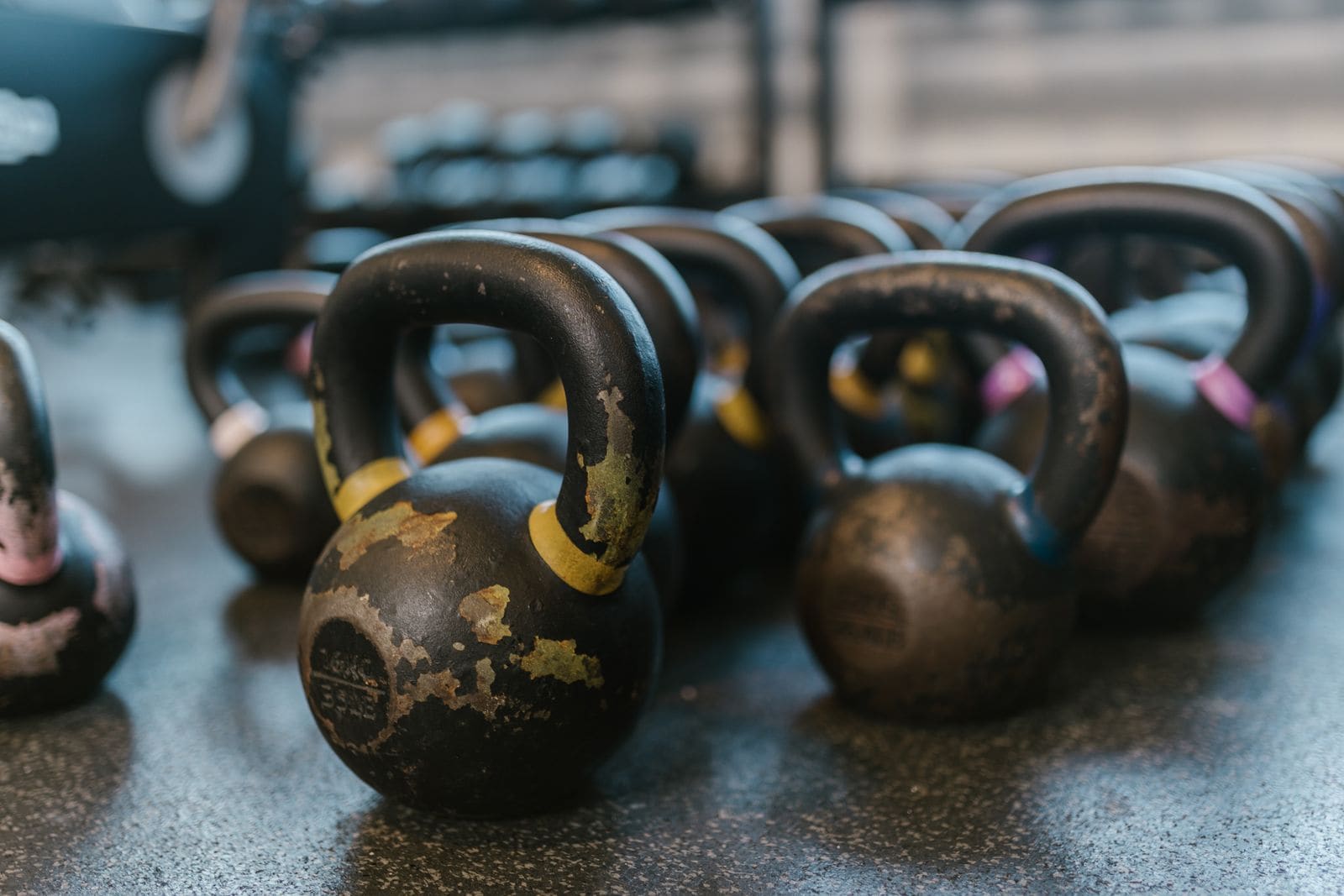 Black kettlebells lined up on a gym floor