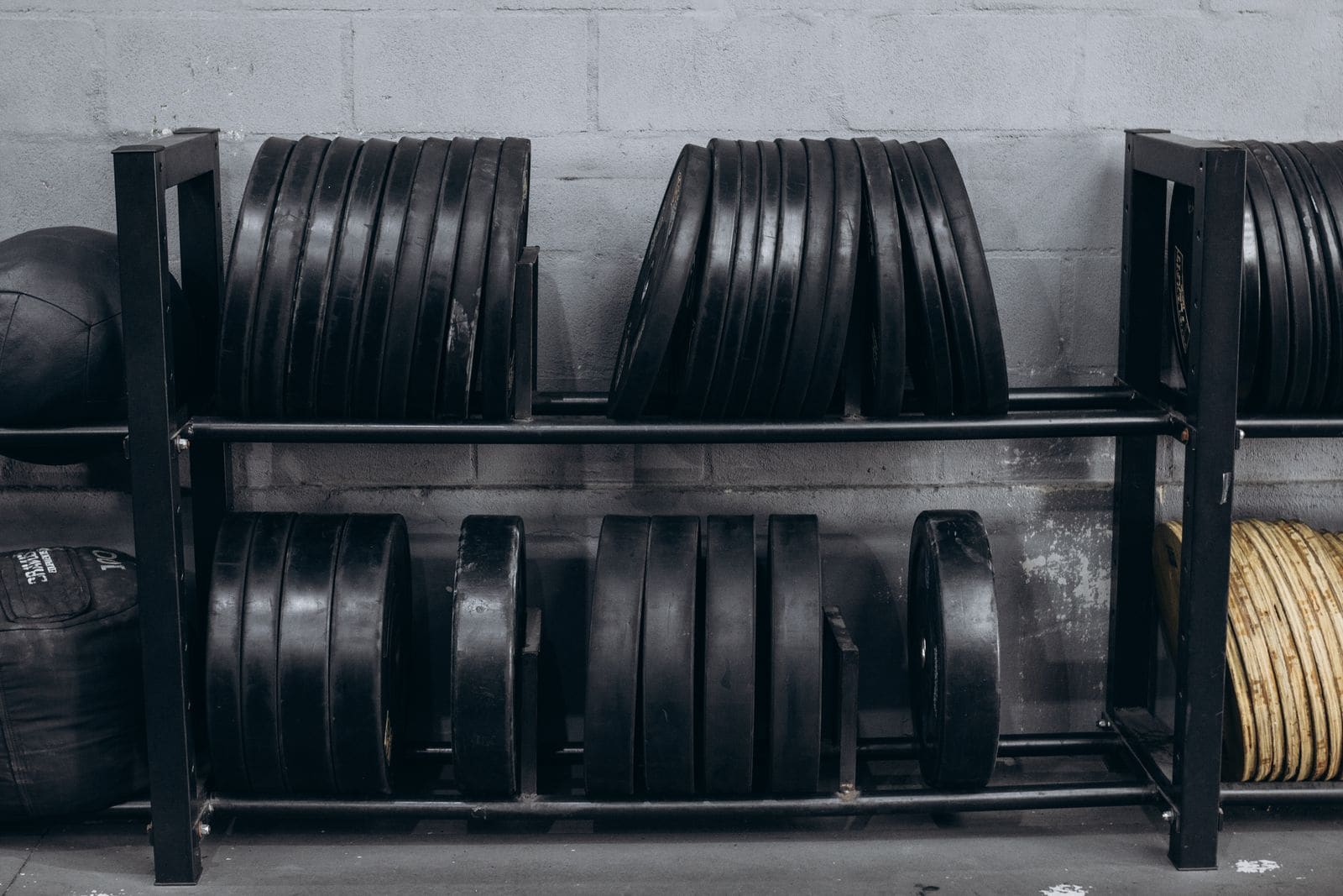 Weight plates stored on a steel rack against a light wall